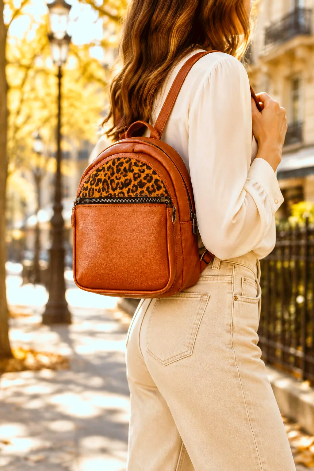 Caipi – Mini sac à dos en cuir cognac et léopard Femme portant le mini sac à dos Caipi en cuir cognac avec empiècement imprimé léopard et poche zippée